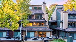 A multi-story residential building with a patio area, outdoor seating, and a garage. - Steps From Snowmass Village Fireplace, Firepit & Mountain Views Aspen Glow Retreat by Avantstay (Snowmass Village)