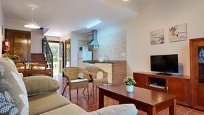Un salon moderne avec un canapé, un téléviseur et un coin repas comprenant des chaises et une table.