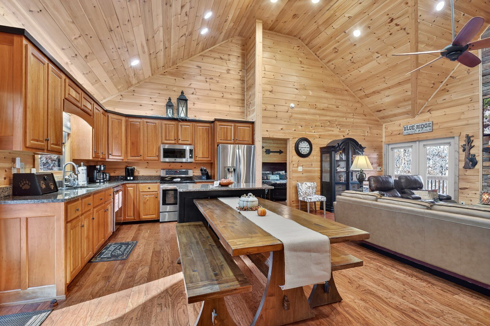 A spacious cabin interior with wooden walls, a large kitchen, a dining area, and a cozy seating area.