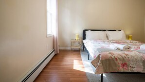 A bedroom with a bed, a nightstand, a lamp, and a window. - Bright and Cozy Cottage in the Heart of Dartmouth (Dartmouth)