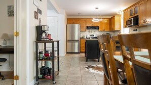 A modern kitchen with wooden cabinets, stainless steel appliances, and a dining area with a cowhide rug. - Bright and Cozy Cottage in the Heart of Dartmouth (Dartmouth)