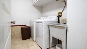 A laundry room with a washing machine, dryer, and a small sink. - Bright and Cozy Cottage in the Heart of Dartmouth (Dartmouth)
