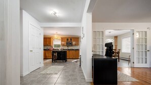 A spacious kitchen with wooden cabinets, a central island, and a dining area with chairs. - Bright and Cozy Cottage in the Heart of Dartmouth (Dartmouth)