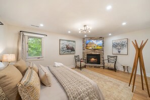 Un dormitorio con cama, chimenea, televisor y ventana con persianas.