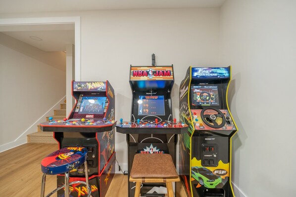 Three arcade machines in a room with wooden flooring and a white wall. - Elegant Retreat in Yonahlossee Resort-Boulder Den (Boone)