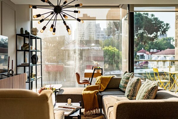 A modern living room with a large window, a unique ceiling light, and a view of the city.
