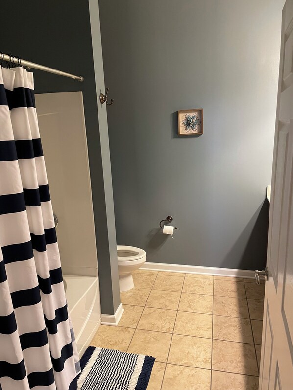 Un baño con bañera, inodoro y cortina de ducha.