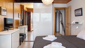 Ein Hotelzimmer mit Bett, Schreibtisch mit Fernseher und einem durchgegangenen Tür sichtbaren Badezimmer.