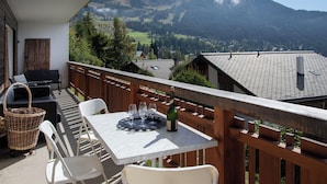 Ein Balkon mit Tisch für zwei Personen, mit Blick auf eine gebirgige Landschaft.