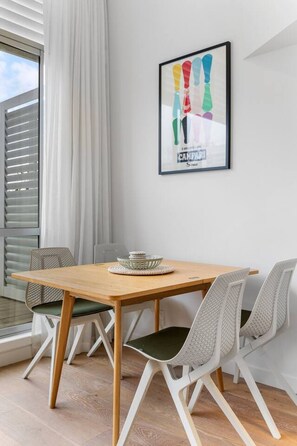 Un comedor con una mesa de madera, dos sillas, un bol en la mesa y una obra de arte enmarcada en la pared.