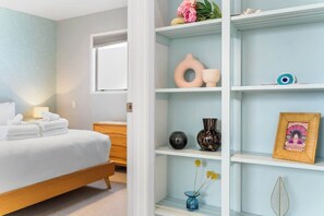 A neatly arranged bedroom with a bed, bedside table, and a shelf with decorative items. - Light-Filled Stay, Steps from Ponsonby w Parking! (Auckland City)