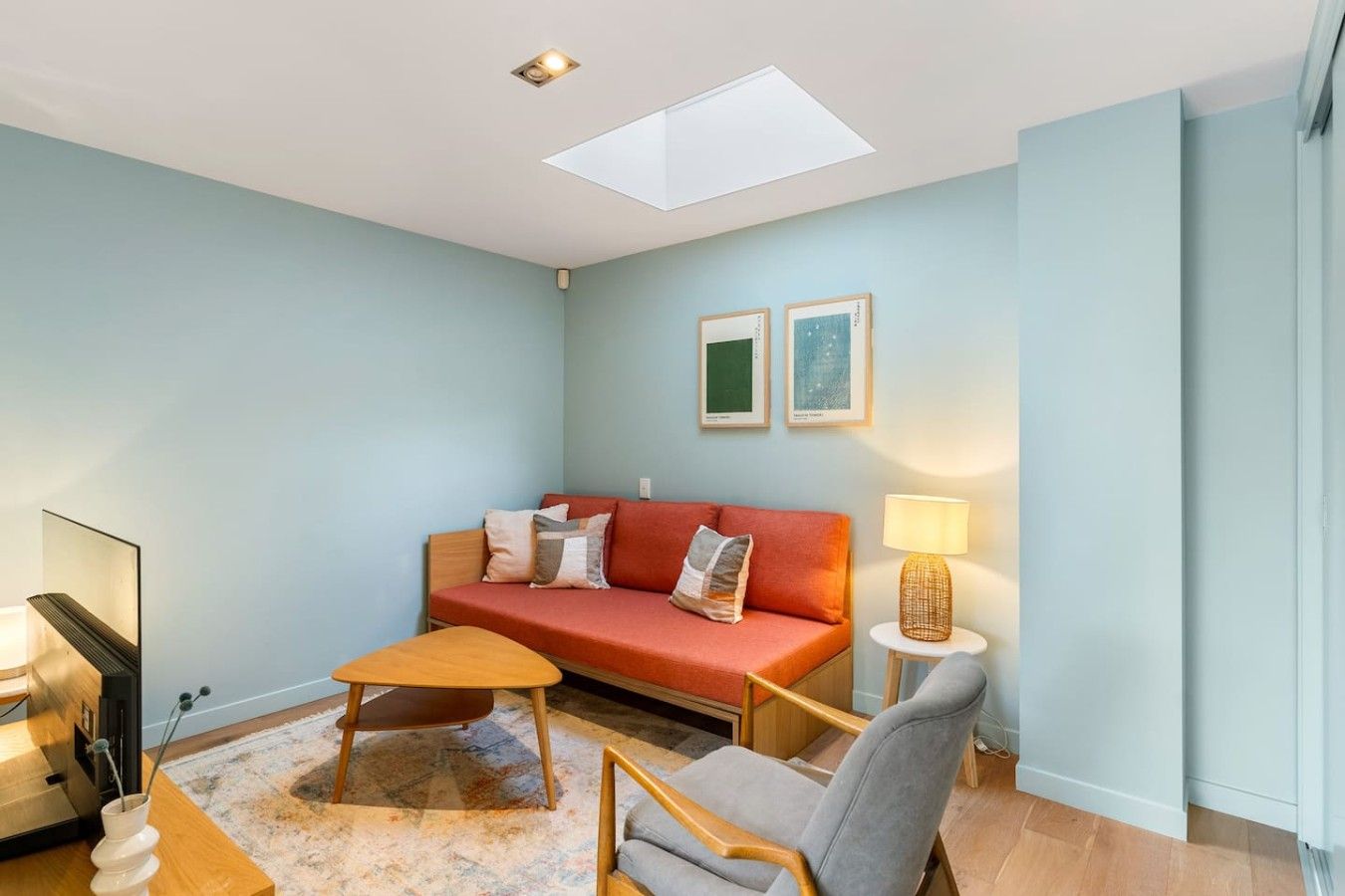 A modern living room with a sofa, armchair, coffee table, and a lamp.