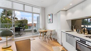 A modern kitchen with a built-in oven and a dining area with a table and chairs.
