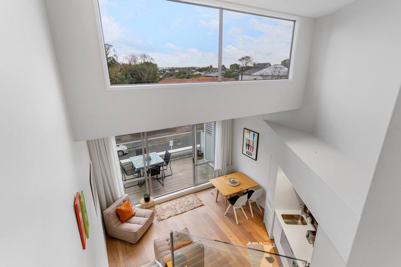 Een modern interieur met een kamer in loftstijl, grote ramen, een eethoek en een trap.