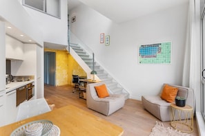 A modern interior with a kitchen, dining area, and seating space with a staircase.