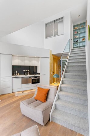 Un interior moderno con una escalera, una cocina y una zona de estar.