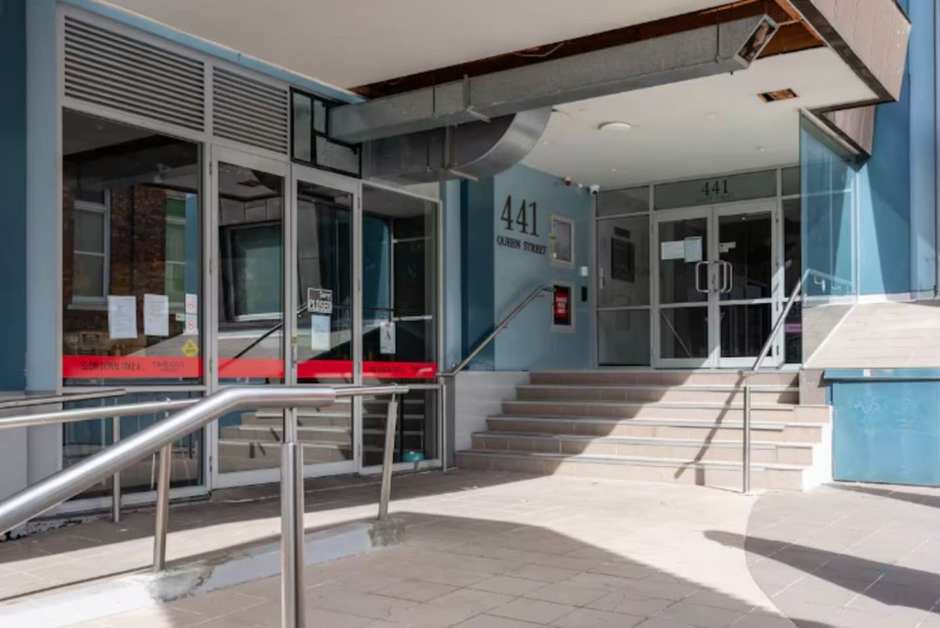 A building entrance with a staircase leading to a door marked '441' and 'Queen Street.'