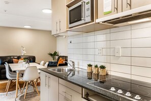 Una cocina moderna con microondas integrado, un lavamanos y una estufa. Hay un comedor con una mesa y sillas.