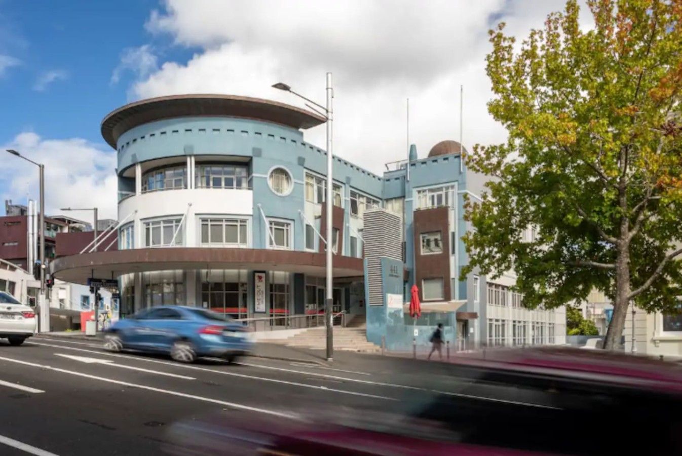 A modern building with a curved facade, multiple windows, and a prominent entrance.