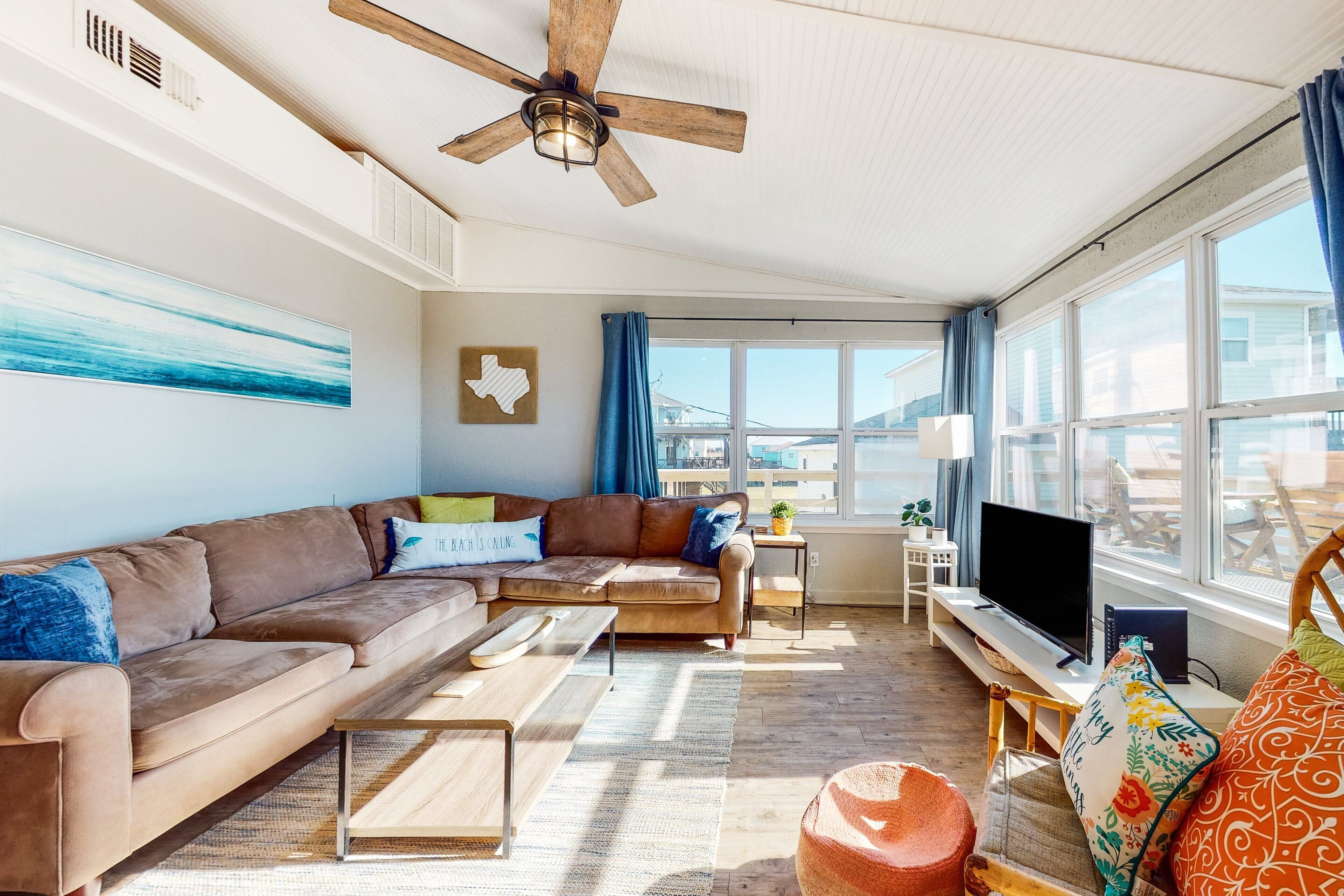 A modern living room with a brown leather sofa, a wooden coffee table, and a television on a wooden stand.