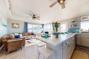 Un vaste espace de vie comprenant un canapé, une table basse et un îlot de cuisine avec un évier et un plan de travail.