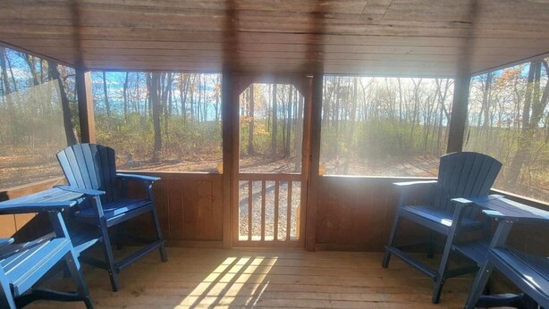 Un'area salotto esterna coperta con due poltrone Adirondack e un pavimento in legno.