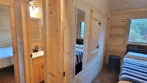 Interno di una baita con due camere da letto, un bagno e una finestra che lascia entrare luce naturale.