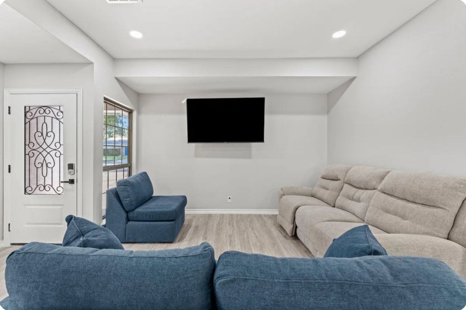 Una sala de estar con un sofá color beige, un sillón azul y un sofá cama azul.