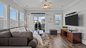 A living room with a grey sofa, a wooden entertainment unit, and a flat-screen TV on the wall.
