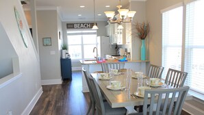 A dining area with a wooden table set for six, surrounded by six grey chairs.