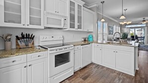 A modern kitchen with white cabinetry, granite countertops, and stainless steel appliances.