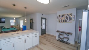 Cozinha moderna com mesa de bilhar, armários brancos e uma grande obra de arte na parede.