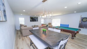 A modern living room with a pool table, a dining table, and a sofa. - Cowboys Tailgate Terrace With pool table (Arlington)