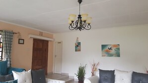 A living room with two sofas, a chandelier, and a door leading to another room.