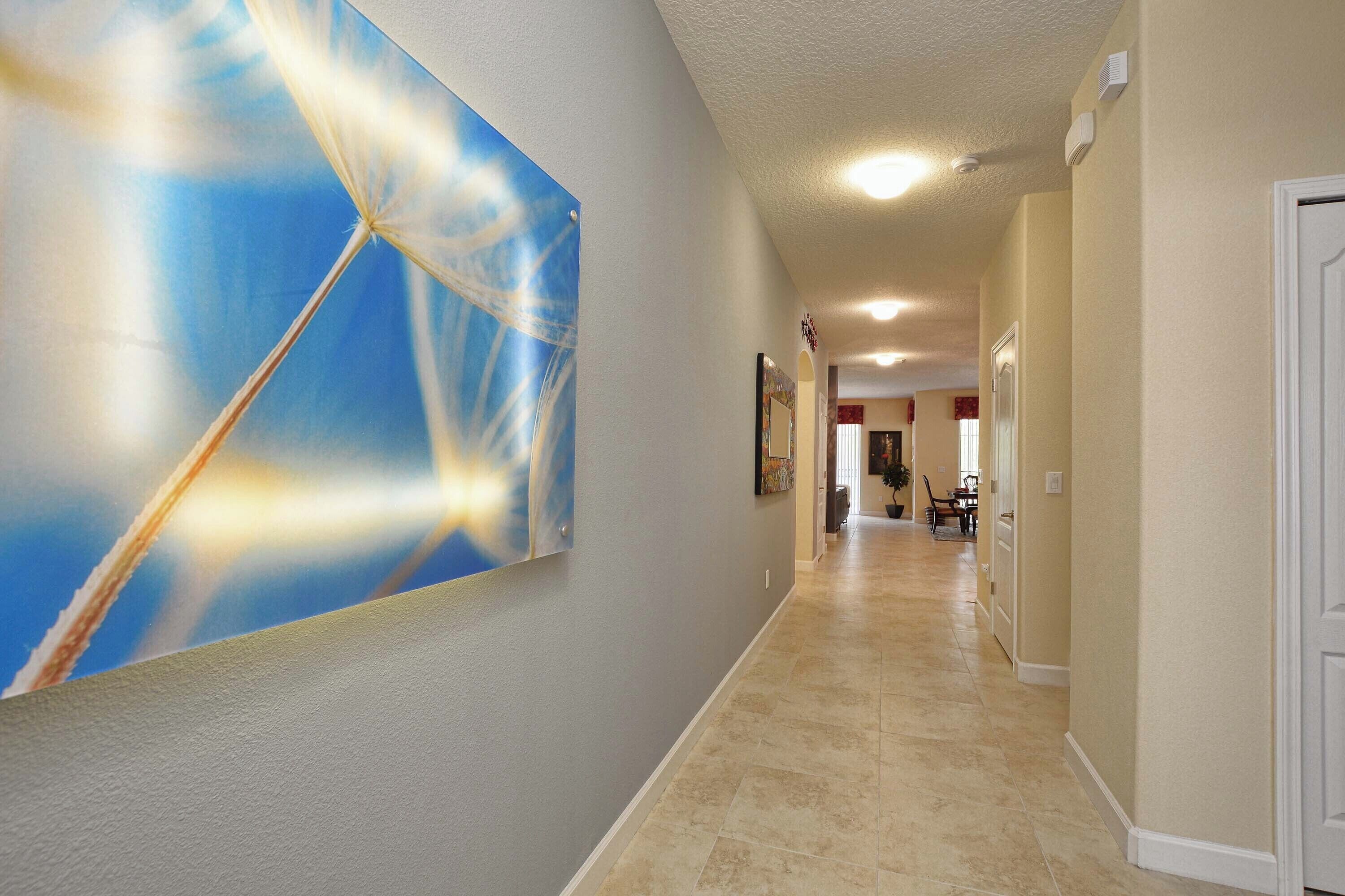 A hallway with a large abstract painting on the left, a tiled floor, and a door on the right.