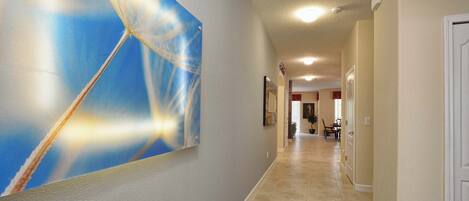 A hallway with a large abstract painting on the left, a tiled floor, and a door on the right.