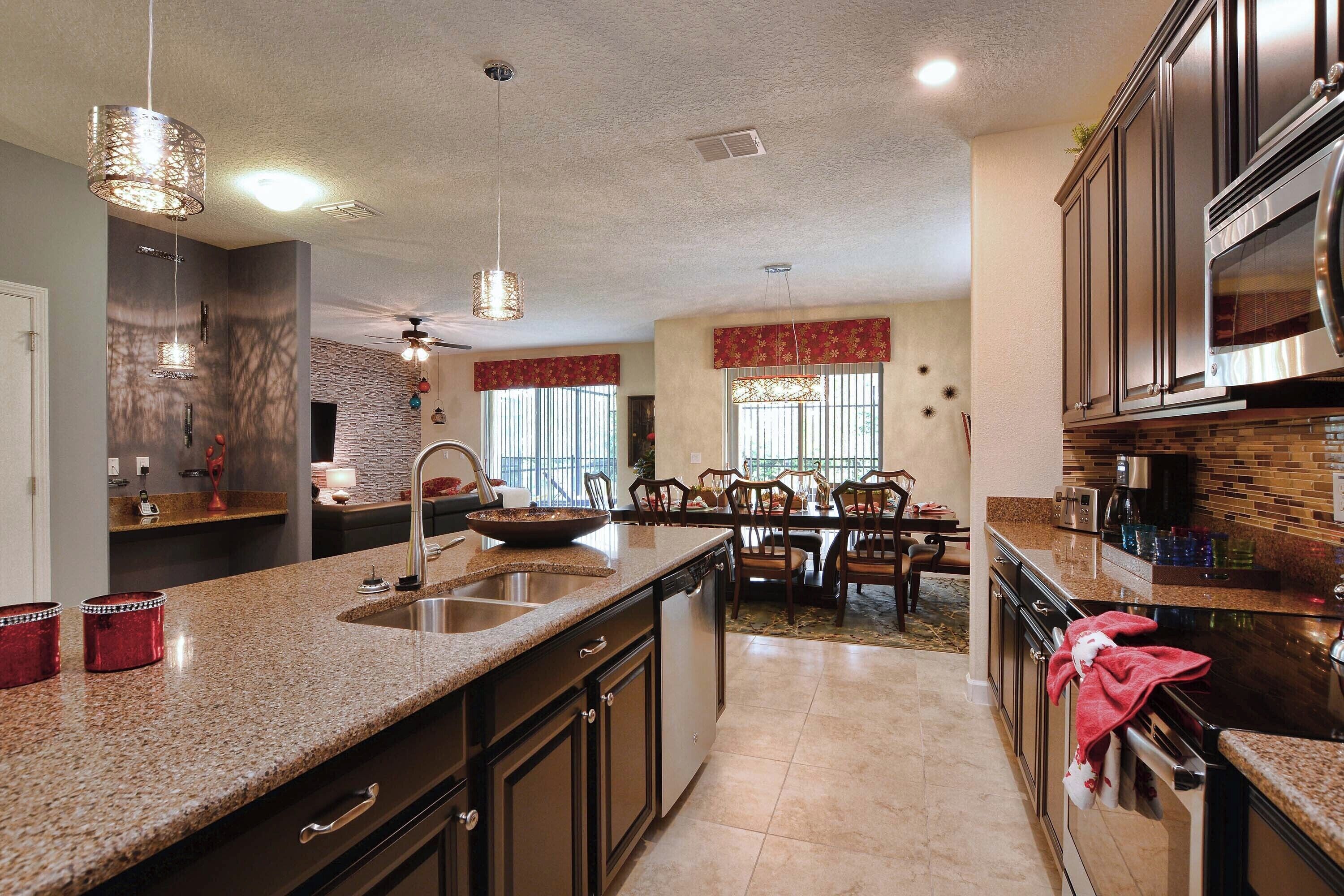 A modern kitchen with granite countertops, stainless steel appliances, and a dining area with wooden chairs and a table.