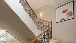 A staircase with ornate metal railings and wooden handrails, leading to a landing with a large window. - 77 by Spacey (#59) | 1BR in Maadi (Maadi)