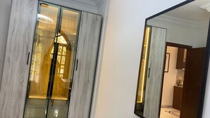A modern bathroom with a large mirror, a vanity with a light, and a red chair. - 77 by Spacey (#59) | 1BR in Maadi (Maadi)