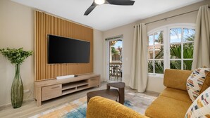 Un salon doté d’un téléviseur à écran plat, d’un mur recouvert de panneaux de bois, d’un canapé et offrant une vue sur l’extérieur.