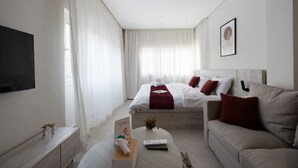 A modern hotel room with a bed, a sofa, a TV, and a reception desk. - 88 Retreat | Chill Vibes + Pool Access by spacey (Maadi as Sarayat Al Gharbeyah)