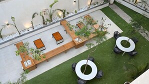 Un giardino pensile con zone relax, fioriere e un tavolo circolare.