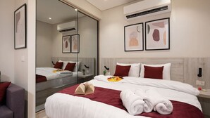 Una moderna camera d'albergo con un letto grande, una parete divisoria in vetro e opere d'arte alle pareti.