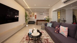 A modern living room with a flat-screen TV, a sofa with colorful pillows, a coffee table with a cake, and a staircase leading to an upper level. - 88 Escape | Pool • Modern • Prime Spot by spacey (Maadi as Sarayat Al Gharbeyah)