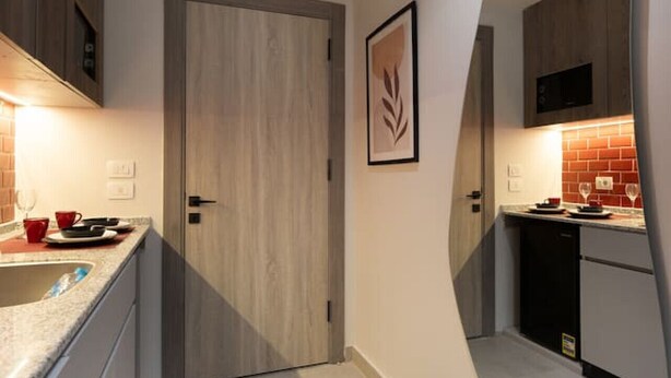 A modern kitchen with a wooden door, a large mirror, and a countertop with a sink. - 88 Escape | Pool • Modern • Prime Spot by spacey (Maadi as Sarayat Al Gharbeyah)