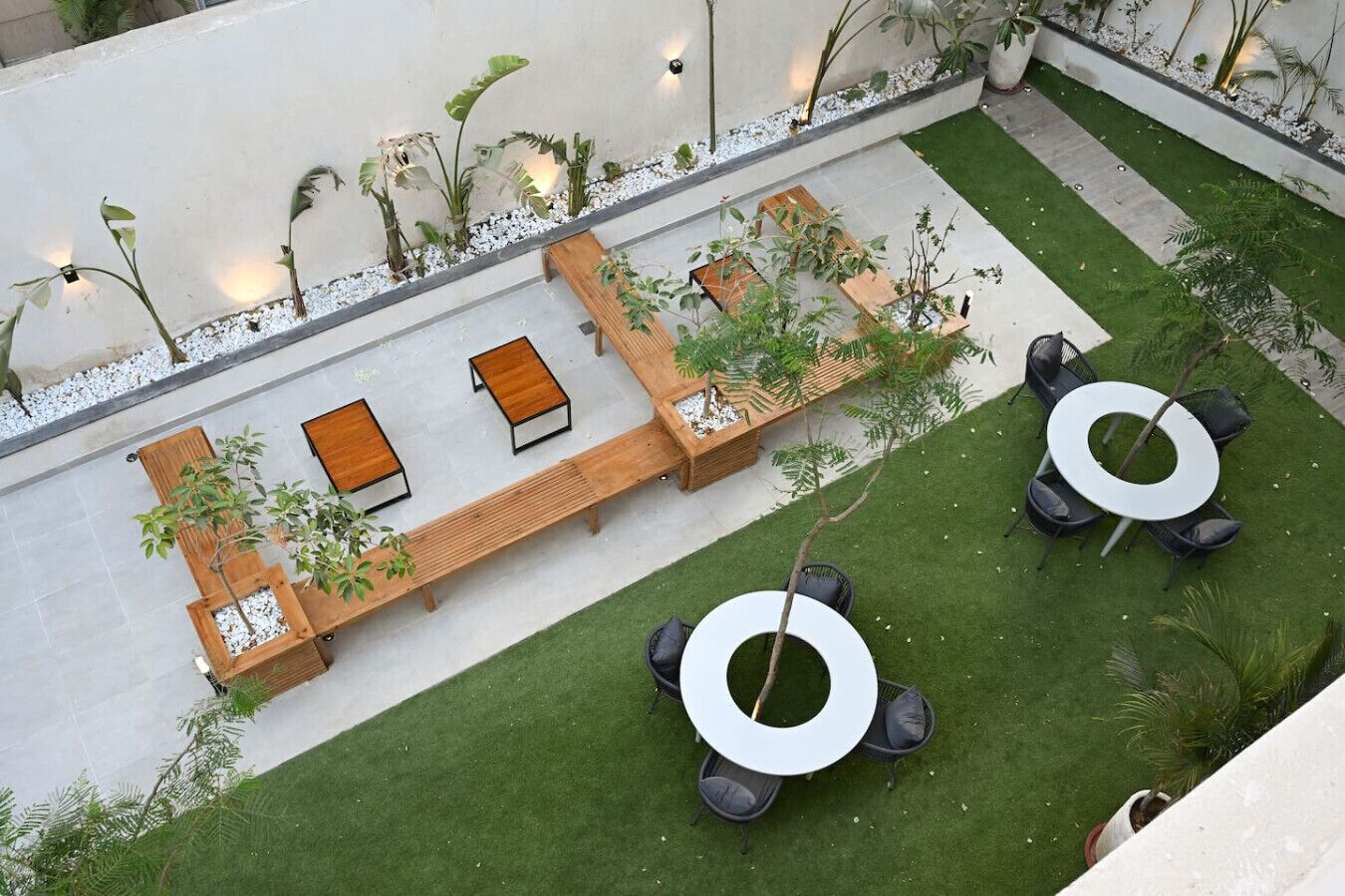 A rooftop garden with seating areas, planters, and a circular table.