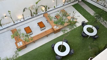 A rooftop garden with seating areas, planters, and a circular table.