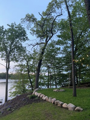 A lakeside area with trees, a stone pathway, and a dock.