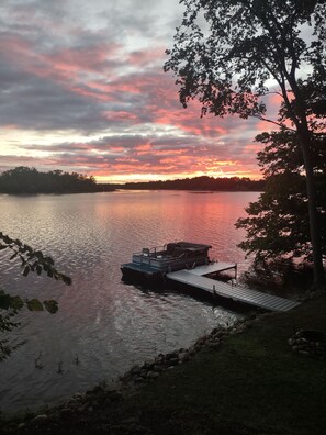 Une jetée s’avançant dans un lac paisible, avec un coucher de soleil en arrière-plan.