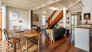Ein großzügiger Wohnbereich mit Esstisch aus Holz, gemütlicher Sitzgelegenheit, einer Treppe und einem einladenden Kamin.